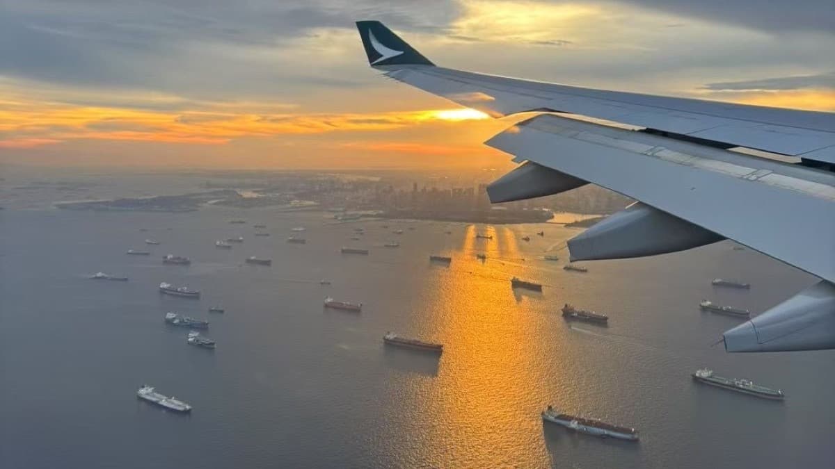 Sunset over the Singapore Strait, seen past an airplane wing and ships below